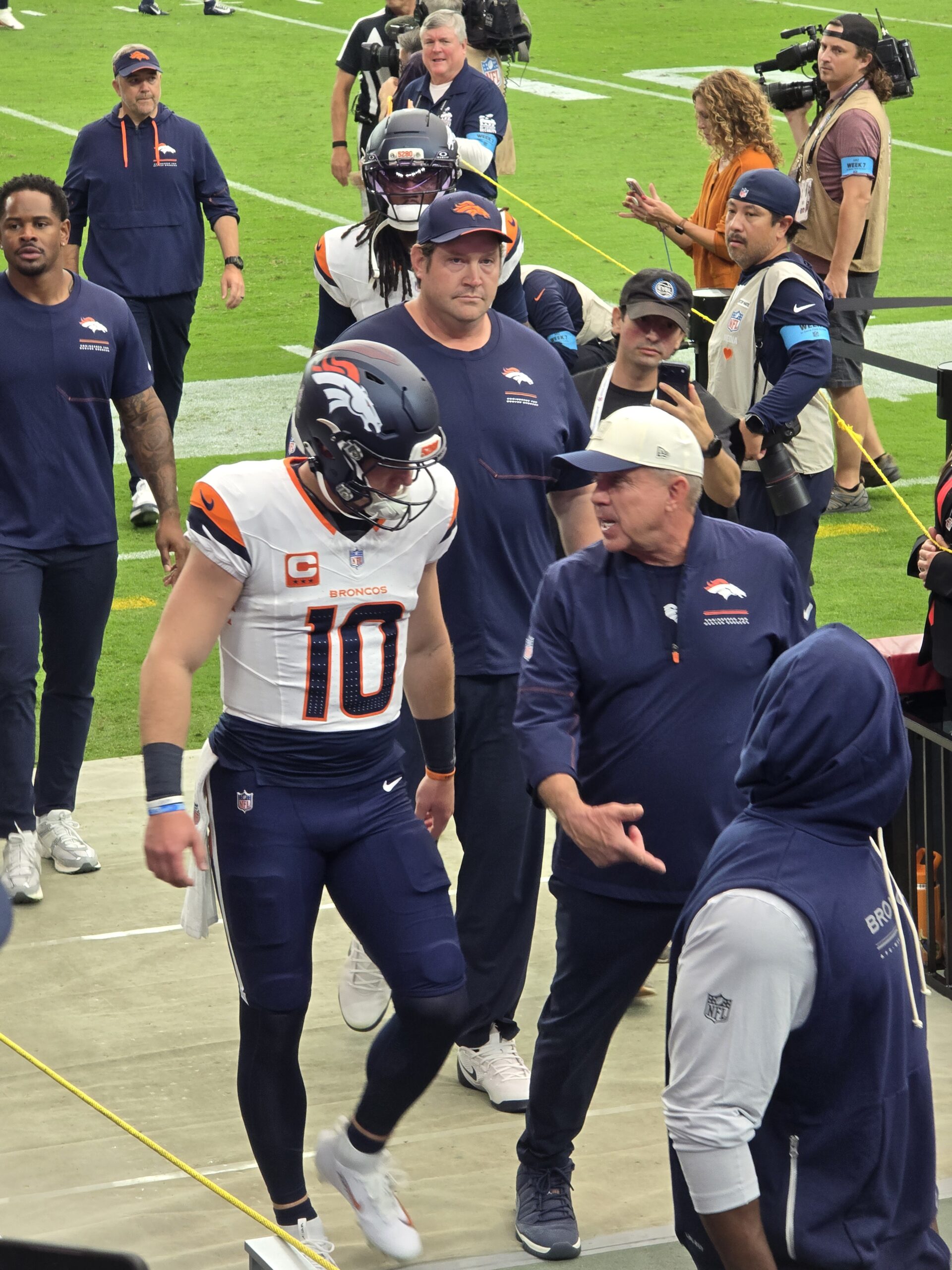Broncos quarterback and coaches walking past the stands by the visitor tunnel