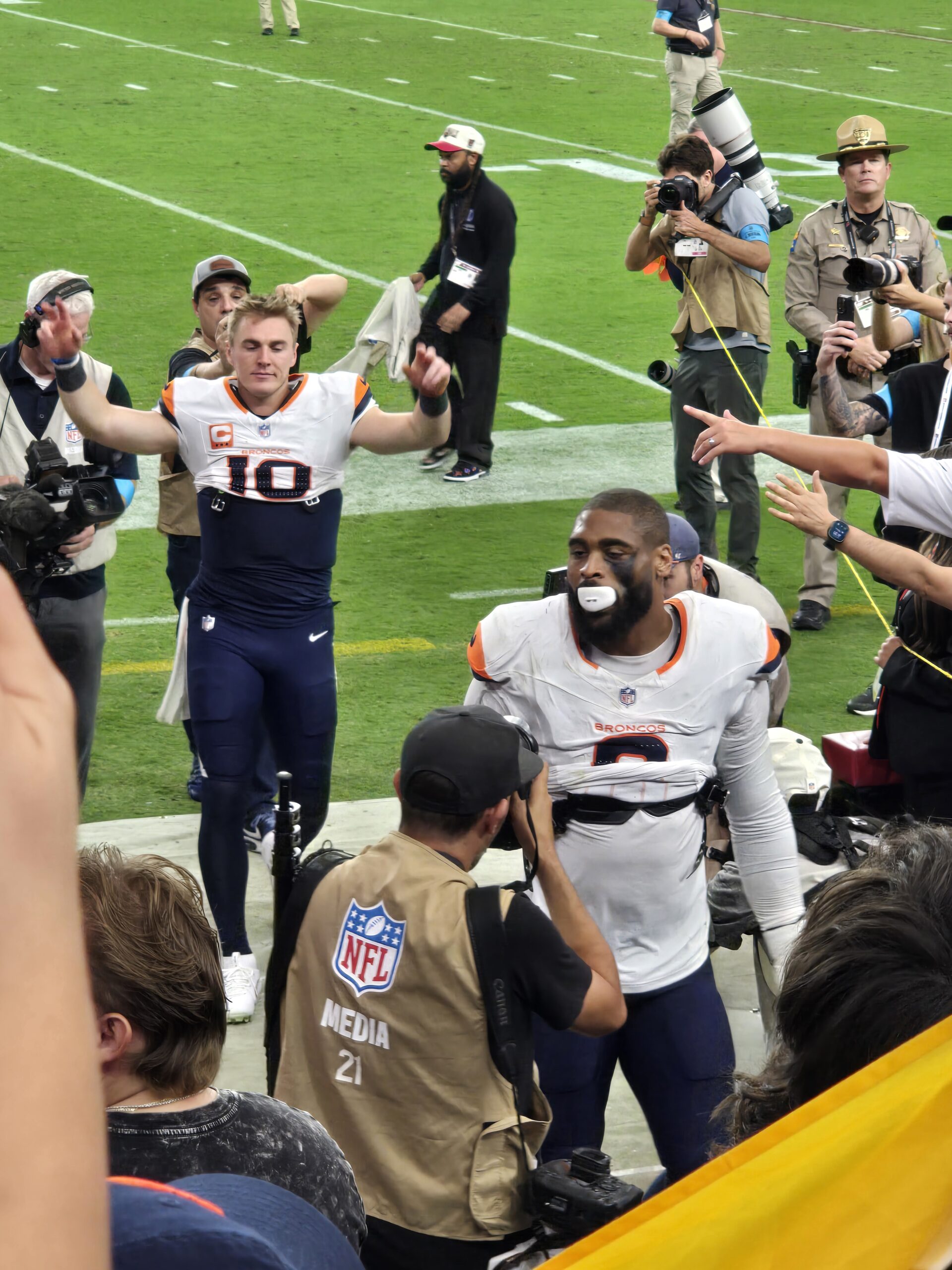 Broncos players celebrating with fans as they leave the field